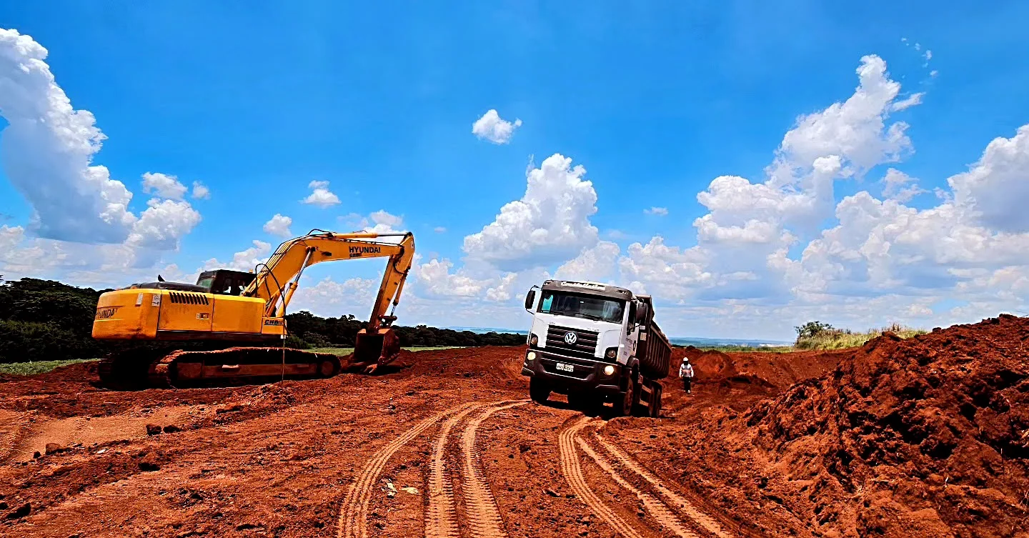 Escavadeira e caminhão em obra de terraplenagem da PS Construtora